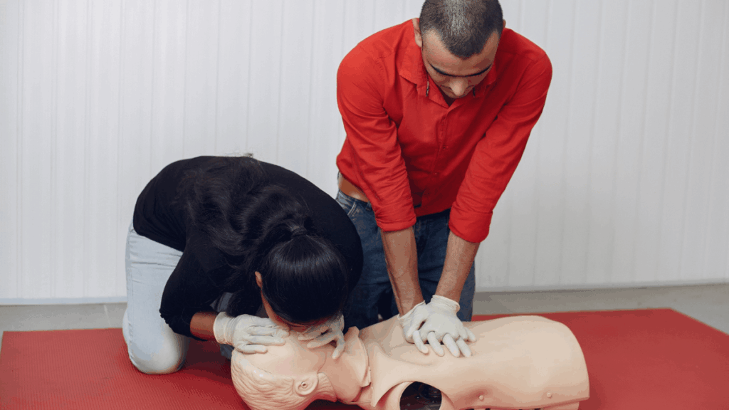 two people performing CPR training on a manikin