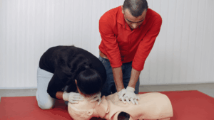 two people performing CPR training on a manikin